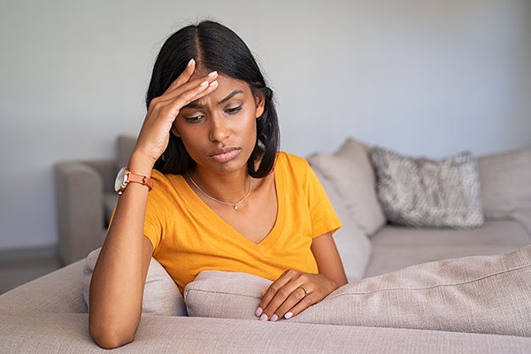 Sad depressed indian woman at home sitting on couch. Stressed yo depressed